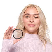 A person smiling and showing a Flex Menstrual Disc